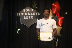 Légende de la photo : Le 22 juin, l'École secondaire Grande-Rivière a organisé une cérémonie spéciale, tout en respectant la distanciation sociale, pour célébrer sa cohorte 2020 - qui comprenait 302 élèves. Sur la photo, Jeremy Souriac sourit alors qu'il reçoit son diplôme pendant l'événement. Photo : J D Potié