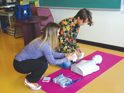 Arthur Mirowski, secondé par son enseignante d'éducation physique, Jessica White, s’est prêté de bonne grâce à une démonstration sur un mannequin d'entrainement au défibrillateur.	Photo: Hélène Périers